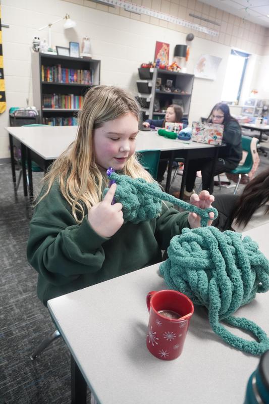 A student uses thick yarn as she crochets.