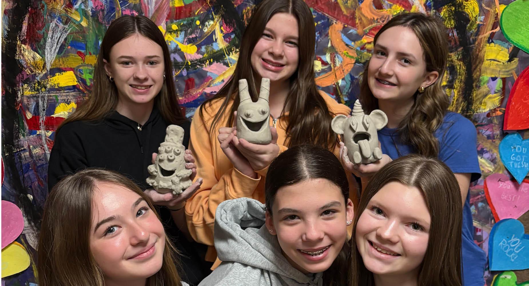 Penn Middle School seventh-grade students hold a clay vessel that the made in art class