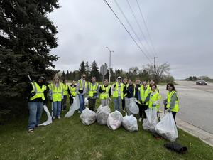 Large group of volunteers posing with filled trash bags after a cleanup effort.