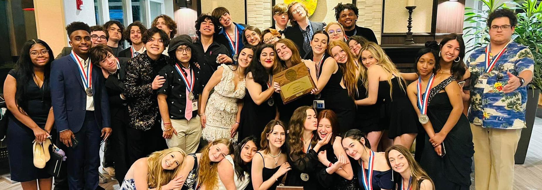 large group of teens wearing medals and holding plaques