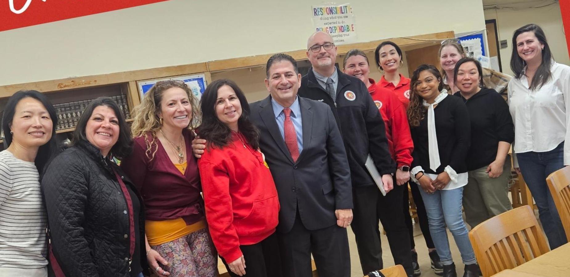 Group of diverse individuals smiling and posing together in a school setting.