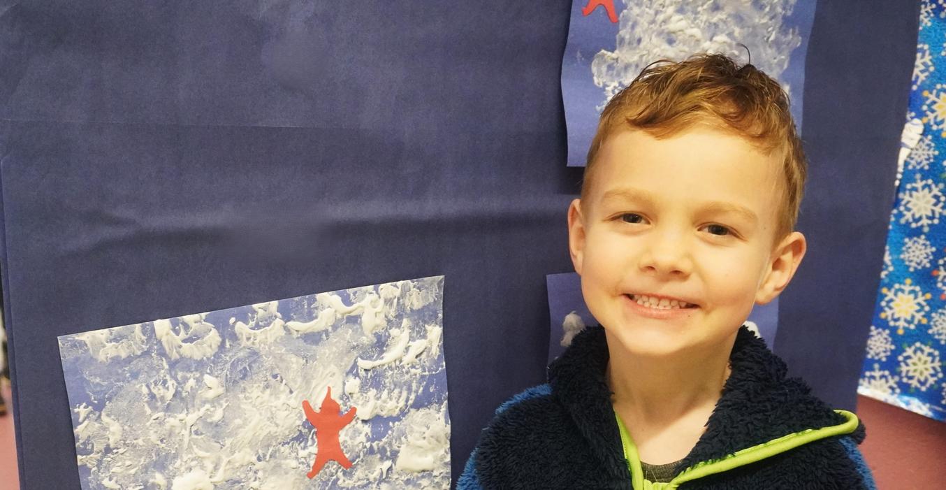 A student stands by a piece of his artwork.