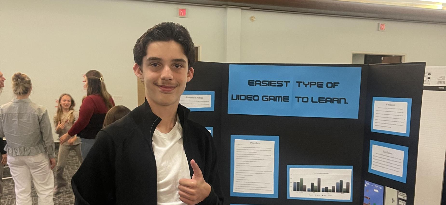 7th grade student standing beside thier science fair board at the annual science night.