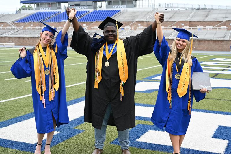 3 Graduating seniors on football field