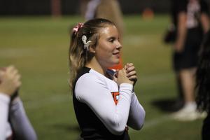 Cheerleader with long hair and a bow, preparing to cheer on the sidelines.