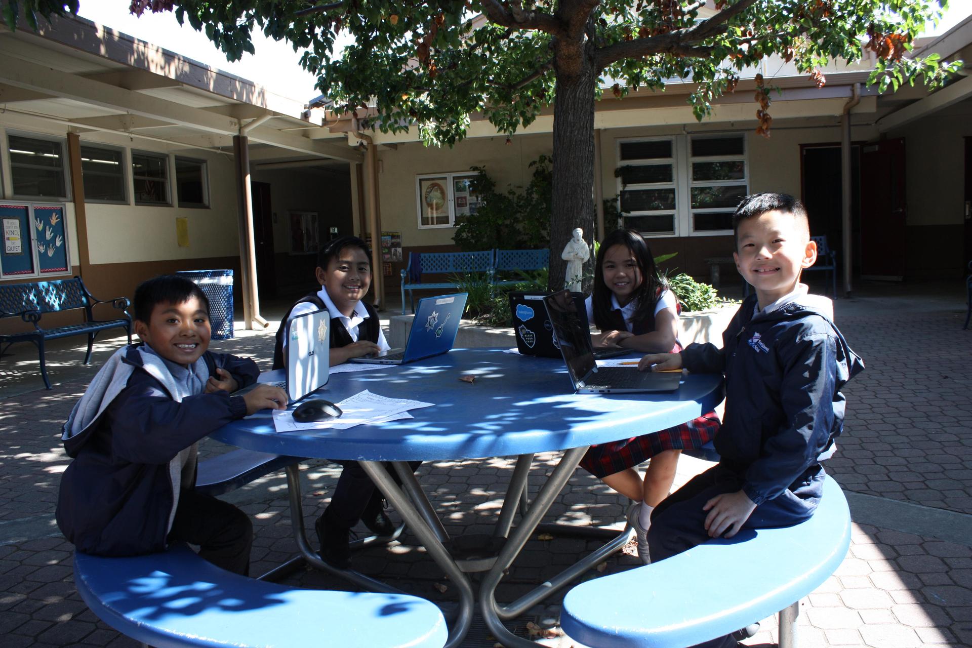 Students sitting at table with laptops