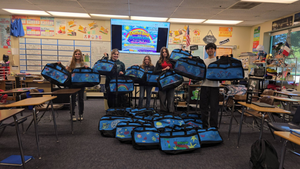 A group of students holding blue decorated bags