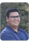 Michael Adella, a man with tan skin and short black hair wearing glasses and a blue polo shirt smiling