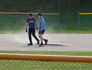 Two students drag a baseball field.