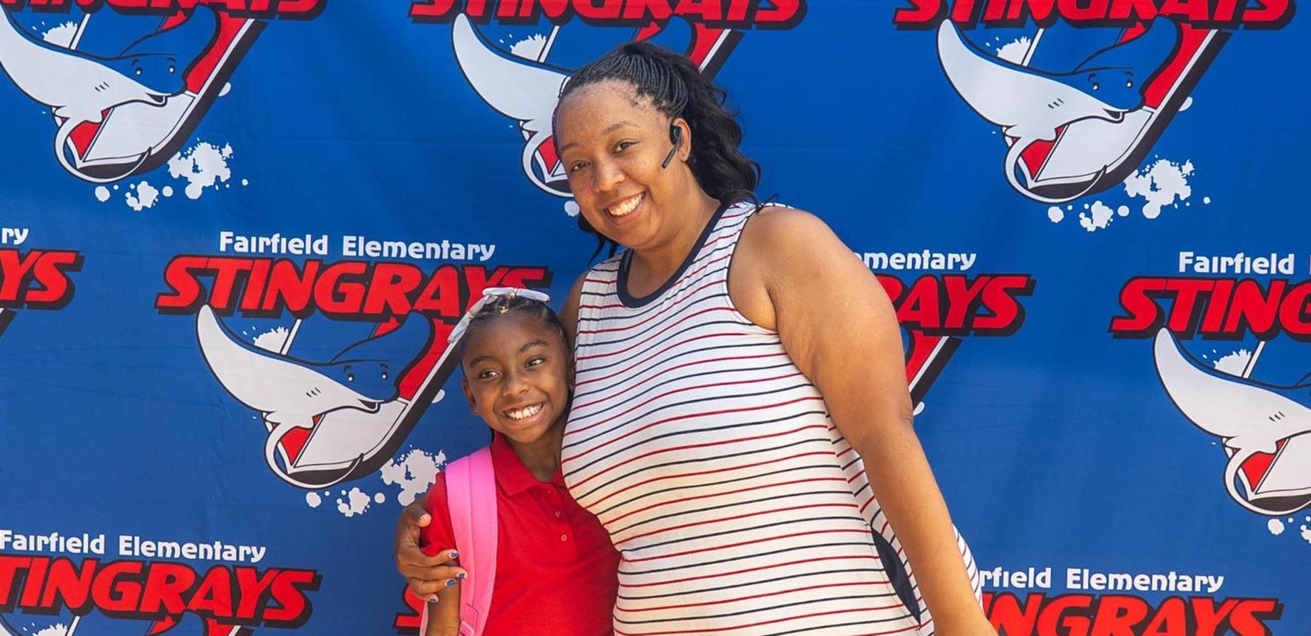 parent and student smiling in front of stingray backdrop