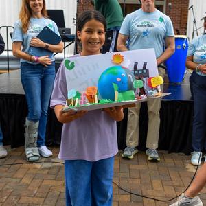 Student posing for picture with their Earth Day poster
