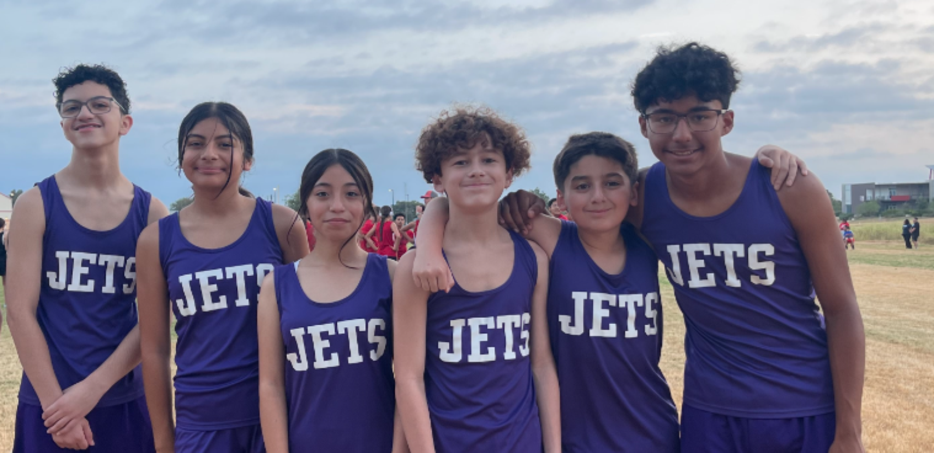 Seven young athletes in purple jerseys standing together in a field.
