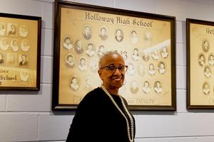 woman in black shirt with graduation photos in background