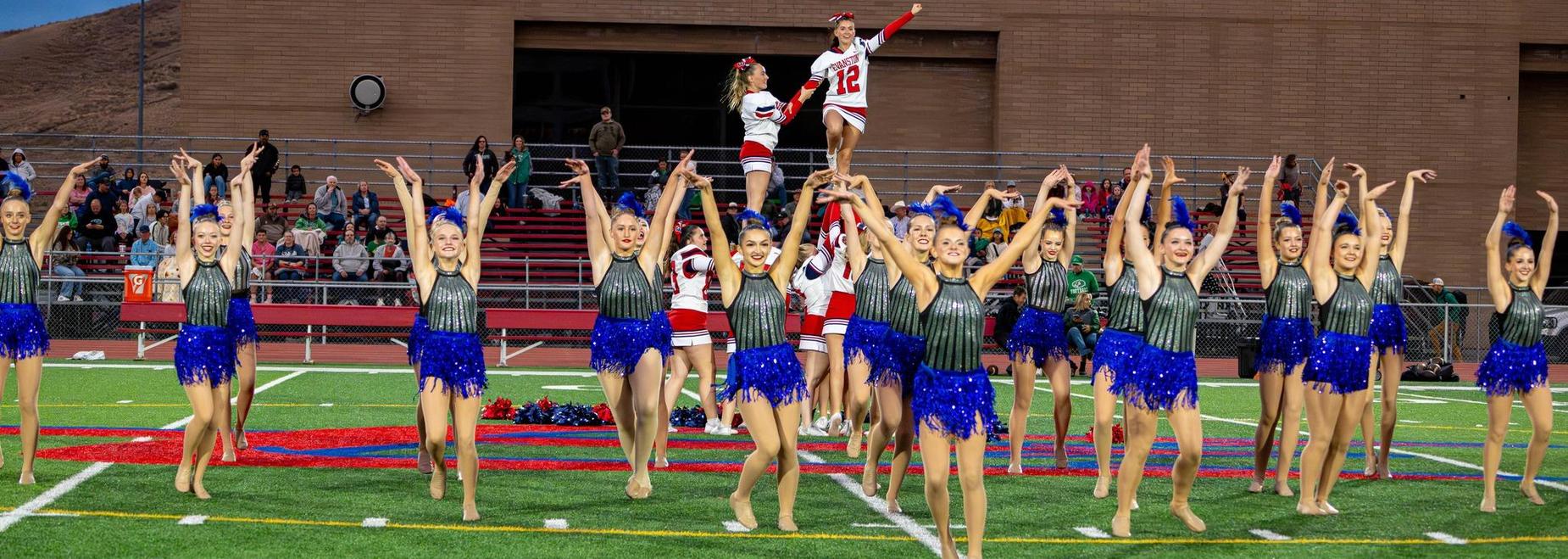 Cheerleaders performing a dance routine on the field.