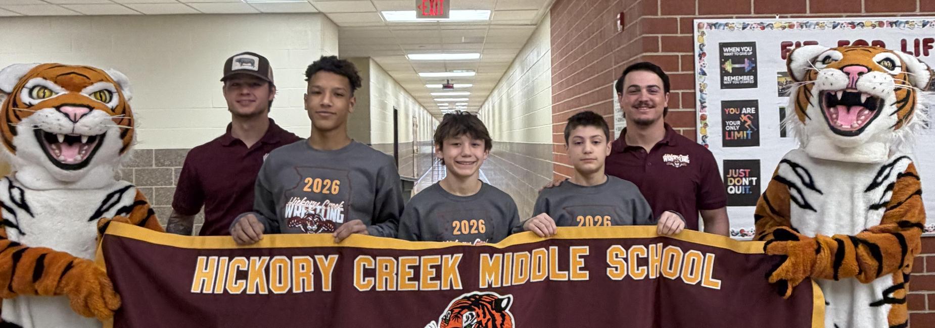 Students and staff holding a banner for Hickory Creek Middle School with tiger mascots.