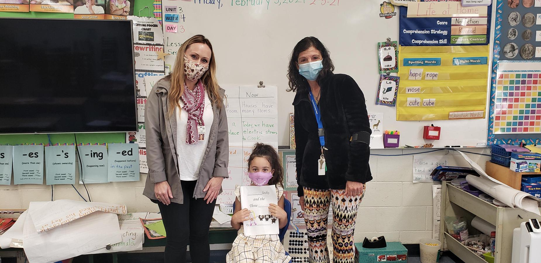 Principal Takaki, Mrs. Bergin and Daniella. Daniella is holding the story she wrote and read to the class