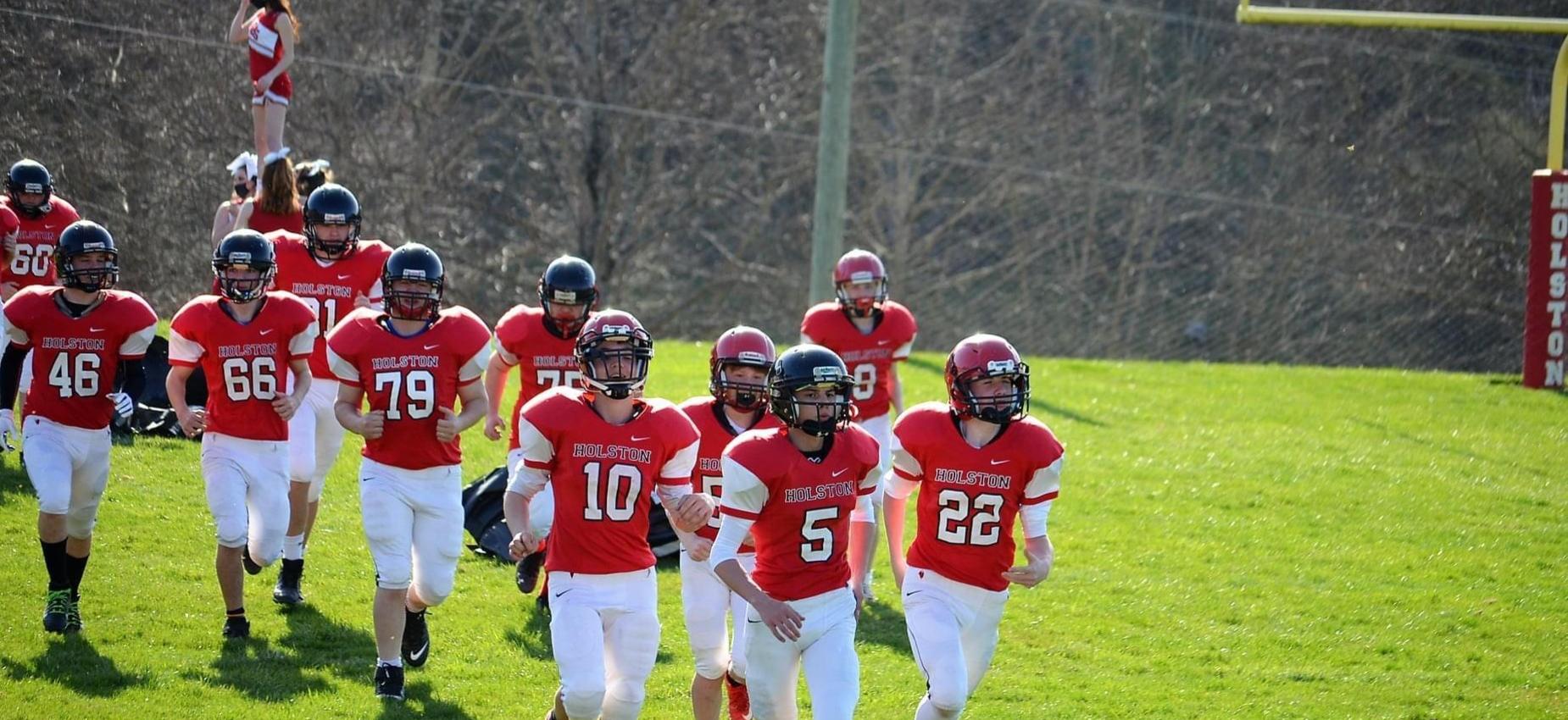 Football players run onto the field.