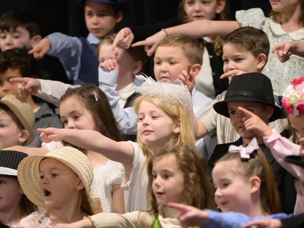 Students wearing hats and pointing during a performance.