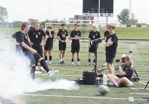A student takes a photo of a soccer player kicking the ball.