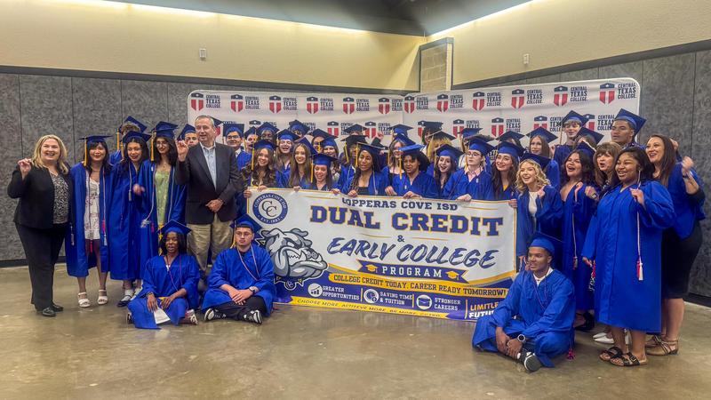A group of students and teachers smiling and holding a banner