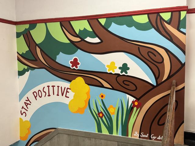 Bright mural with trees and flowers featuring a positive message.