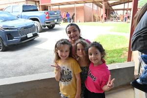 A girl poses with three younger girls, all smiling and making peace signs.