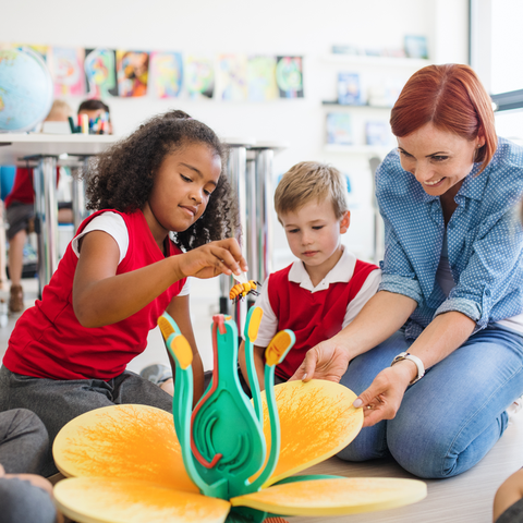 Children engaging with a flower model while a teacher guides them.