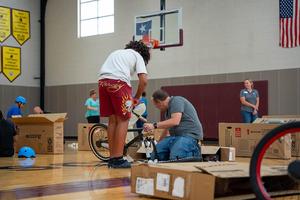 A student works with a mentor to assemble a bicycle