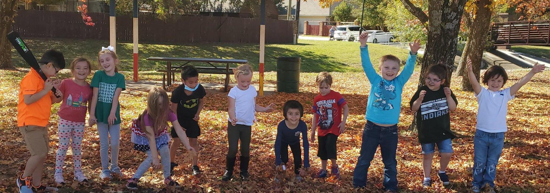 group of kiddos playing in fallen leaves