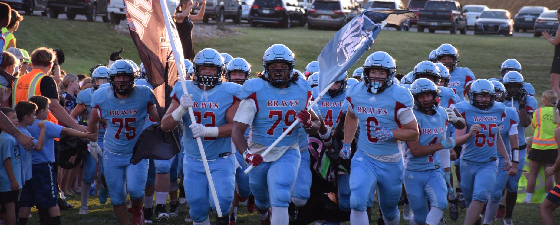 Football team running onto field with flags