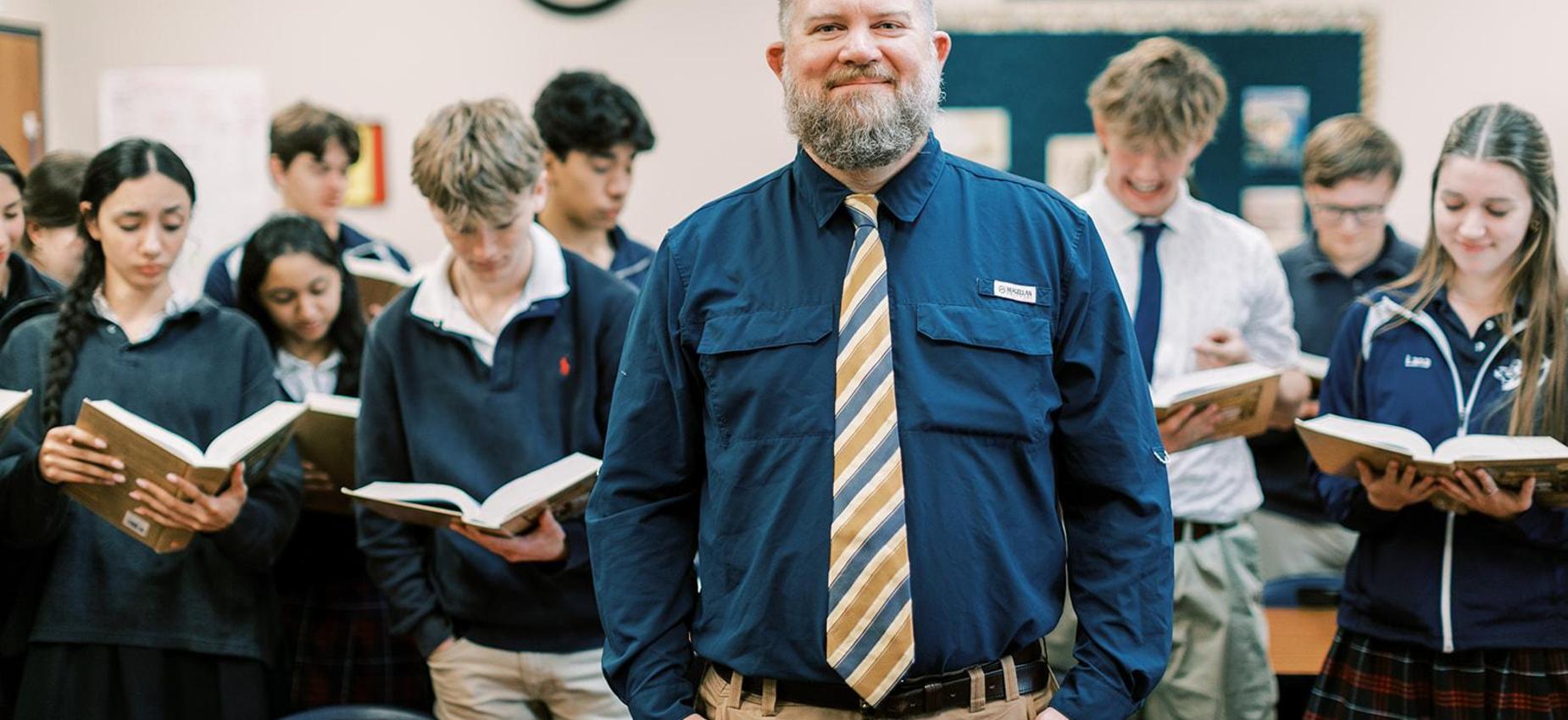 Teacher stands with high school students holding open books