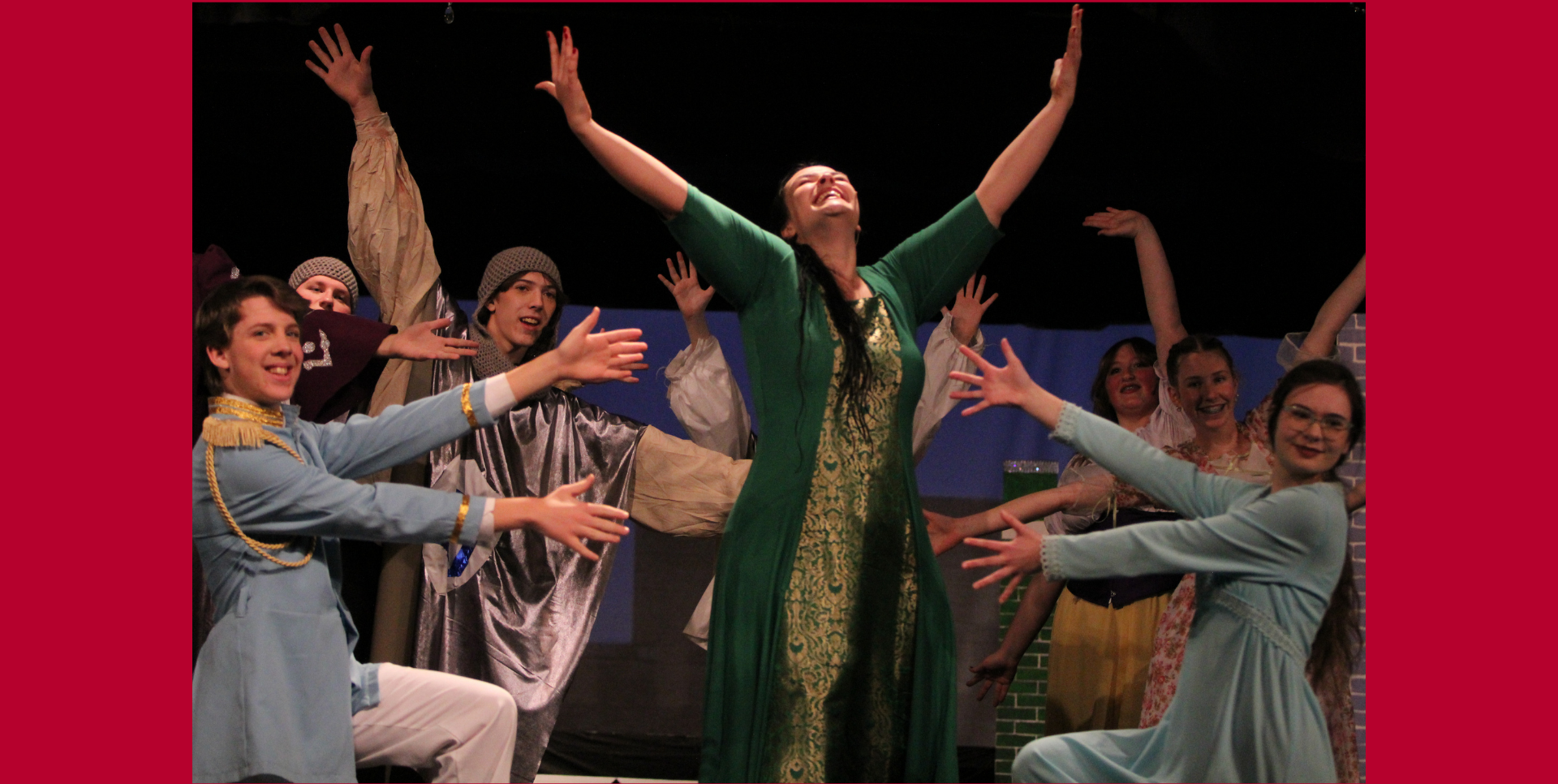 A joyful theater performance with actors in costumes posing dramatically.