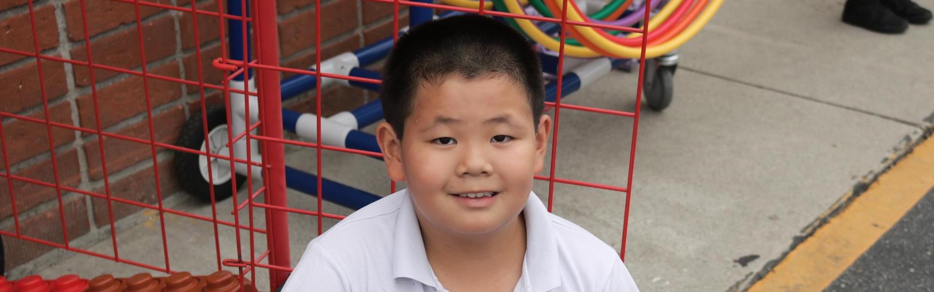 Boy sitting in front of a toy cart with building blocks.