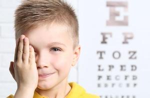 child with hand over one eye and an eye chart