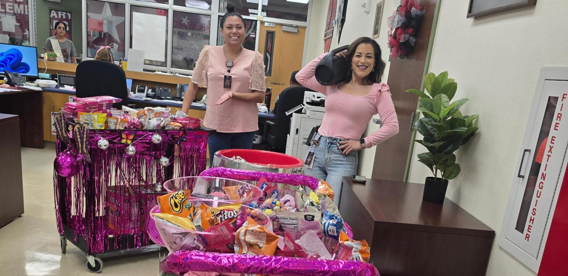 A vibrant snack cart filled with treats and two smiling staff members.