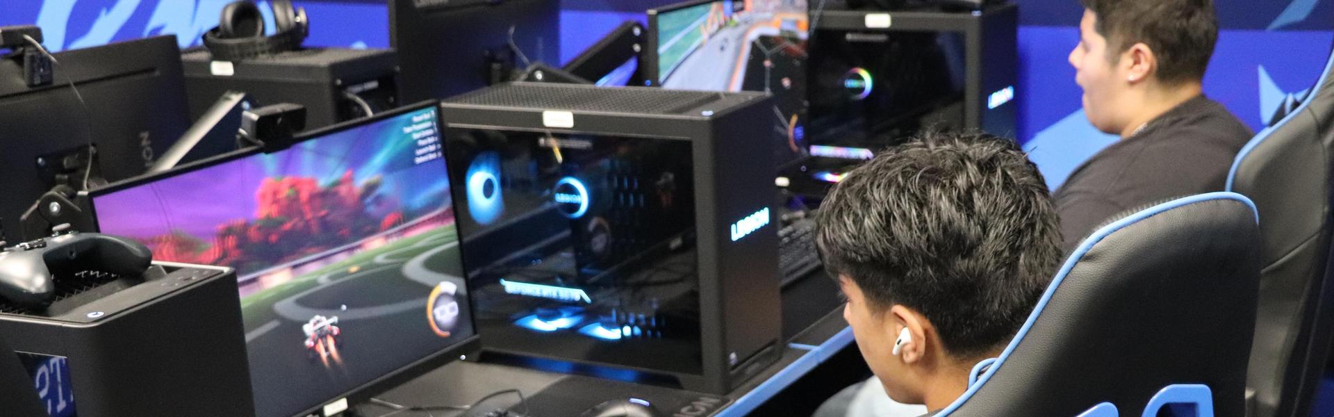 A person gaming at a computer with multiple screens and gaming equipment.