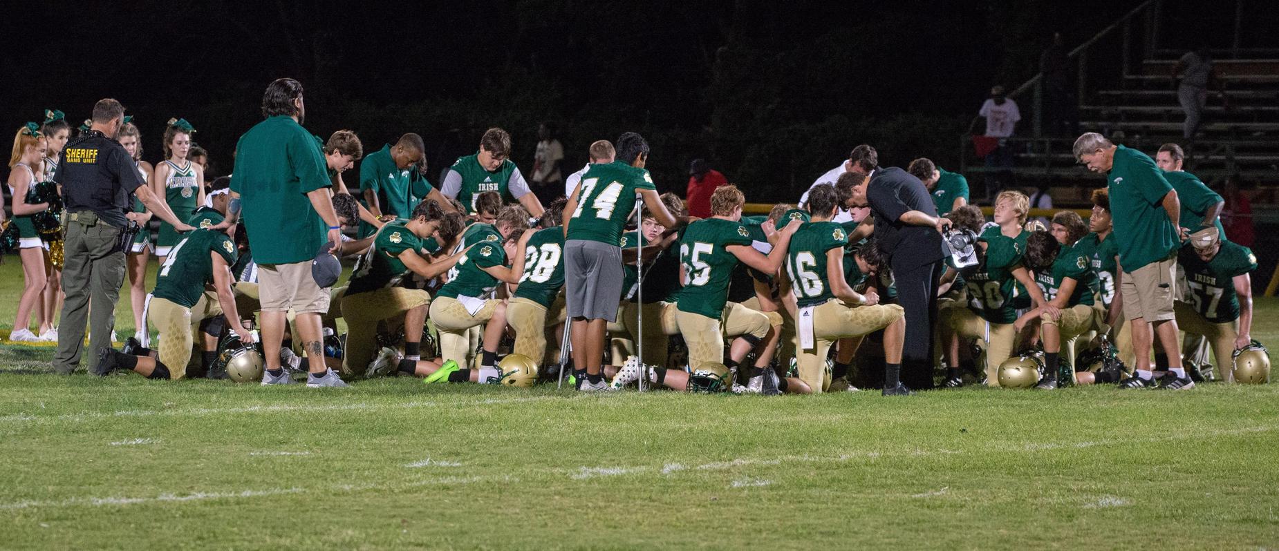 Football team praying after game