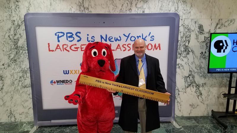 big red dog costume standing next to superintendent