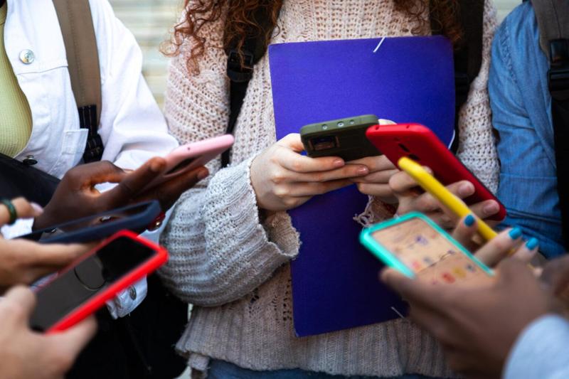 A group of people holding smartphones while one has a clipboard.