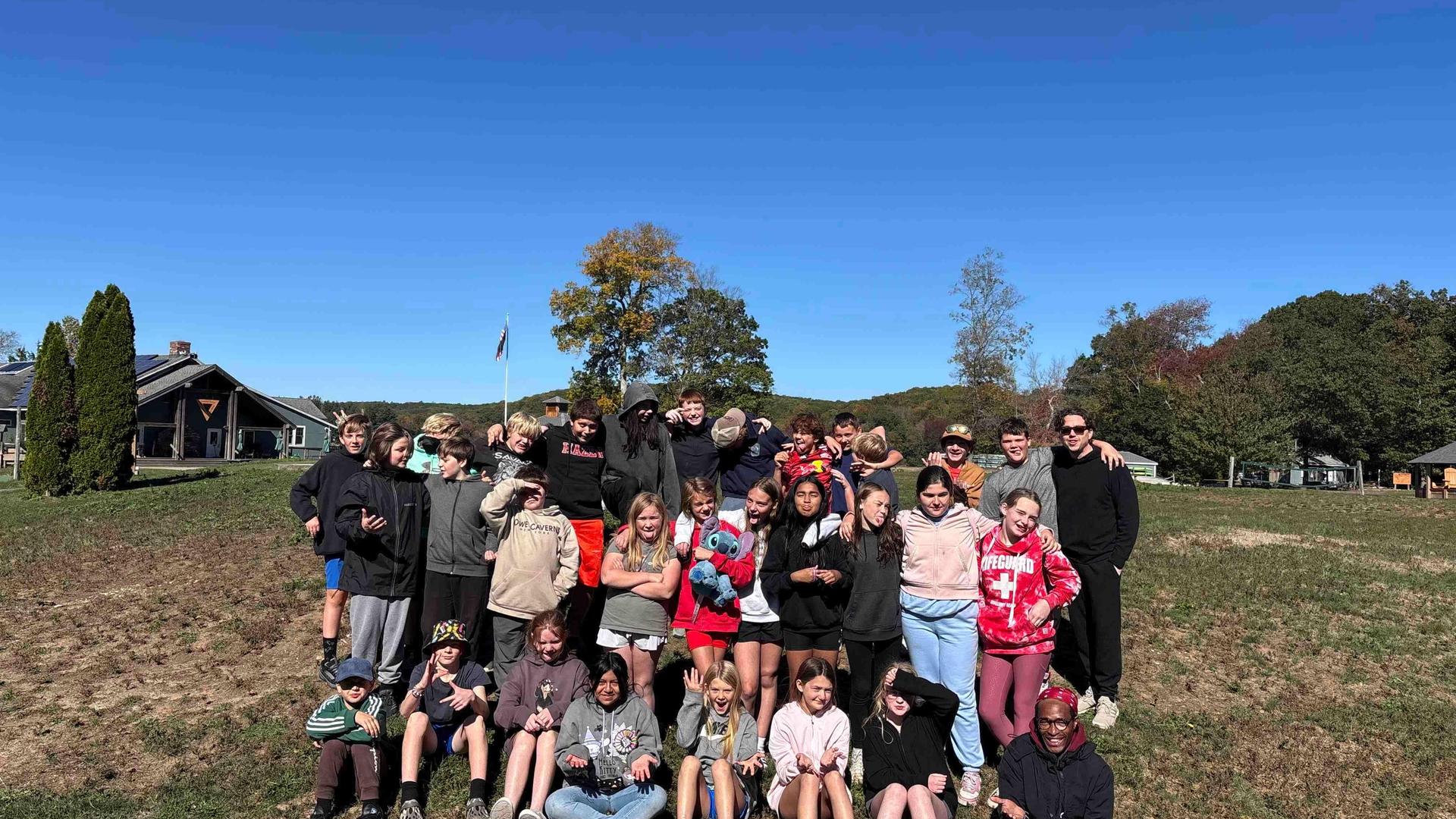 Group of children and adults posing outdoors on a sunny day.