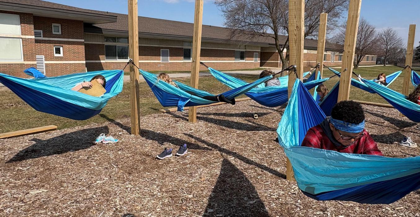 Students relaxing in blue hammocks on a sunny day outdoors.