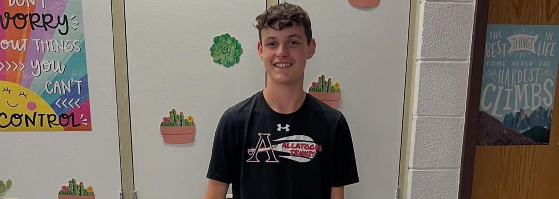 Boy standing in front of a door decorated with plant stickers, wearing a black shirt and pants.