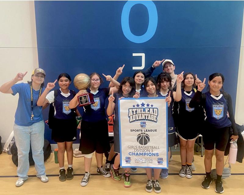 Basketball team poses with Championship banner