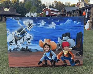 Two children pose with scene board created by ATC students and painted by art students.