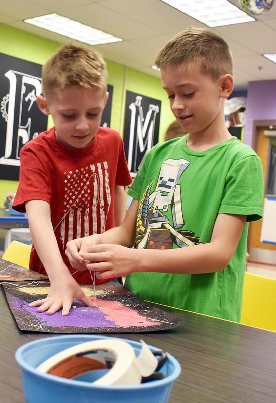two boys tying a piece of string