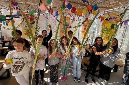 Group of children holding decorative palm branches in a festive setting.