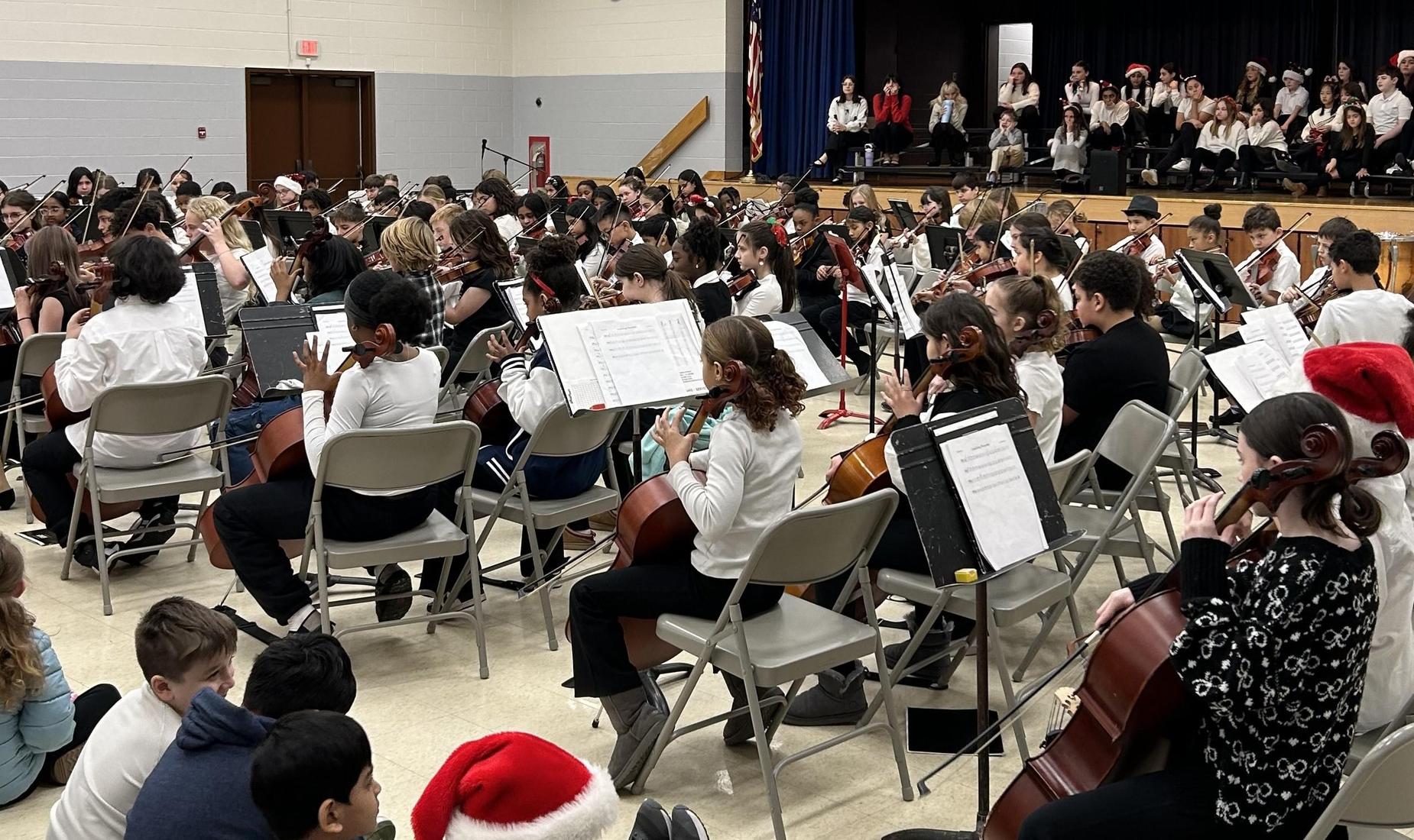 A large group of musicians performing in concert, wearing festive attire.