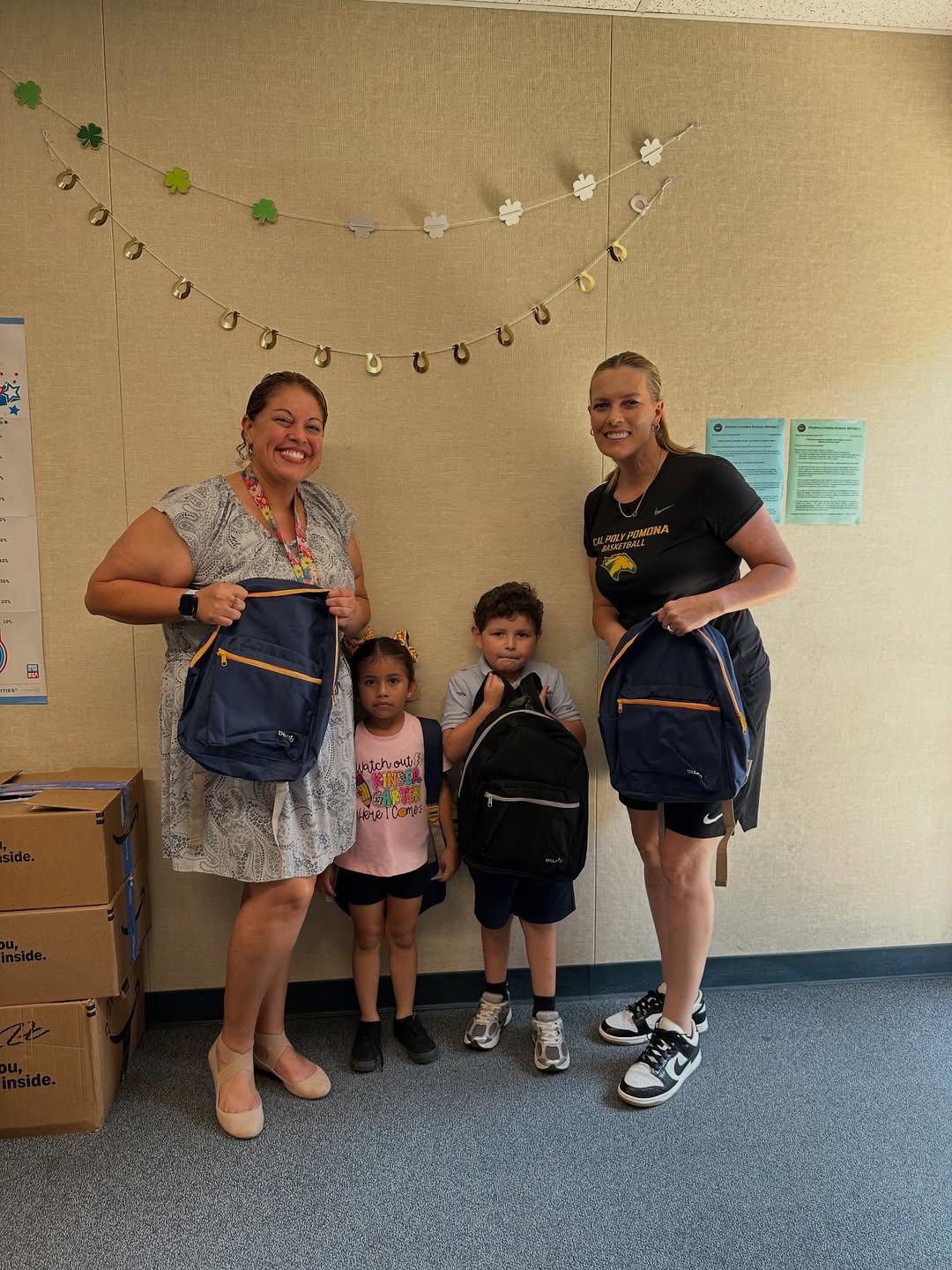 four persons 2 adults and 2 children holding backpacks