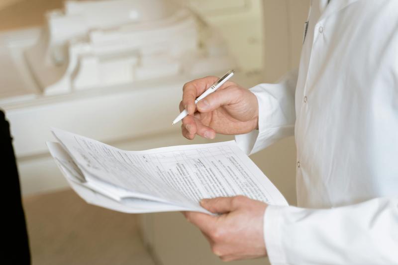 medical forms being held by someone in a lab coat