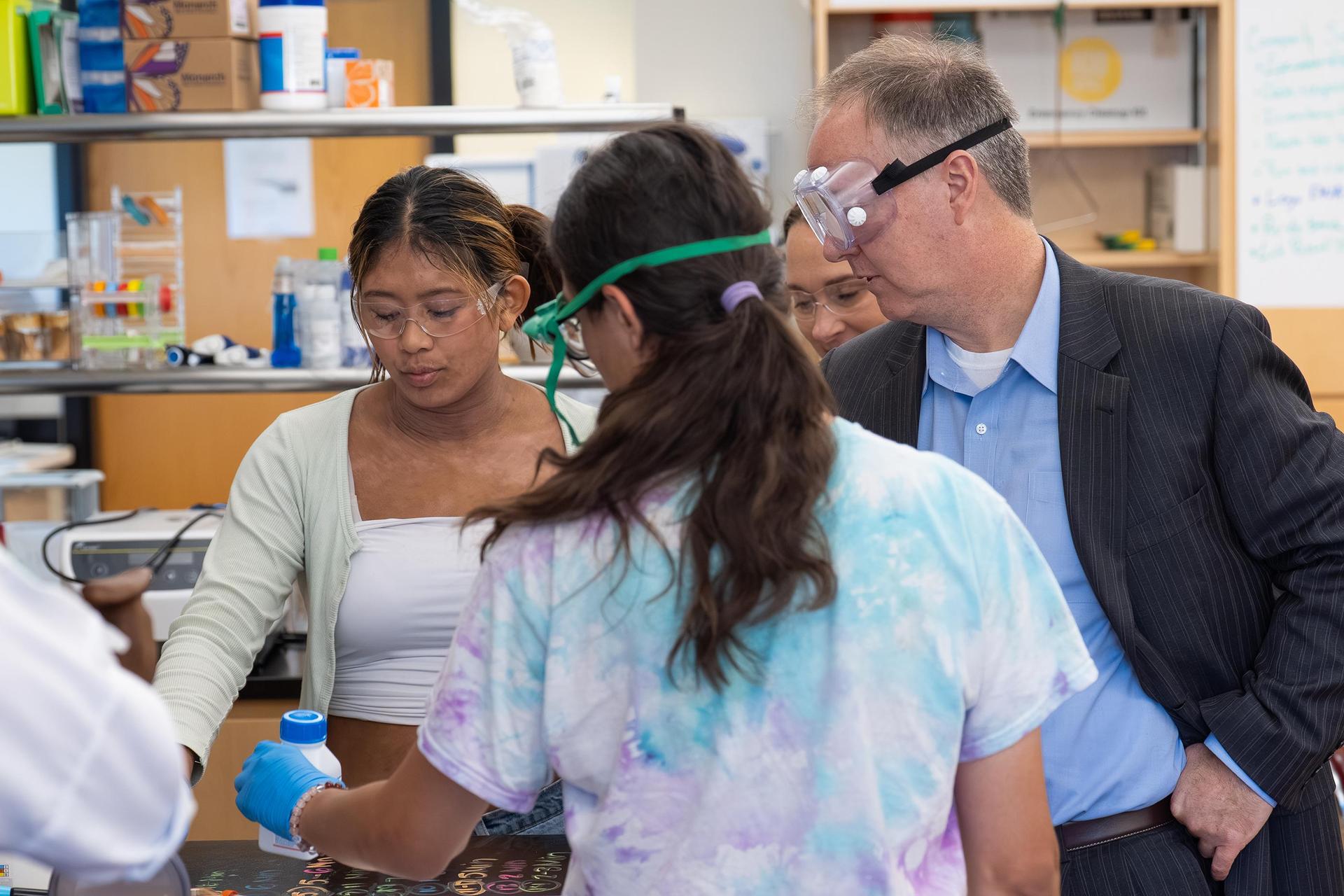 Adults observing students during a hands-on science activity in a laboratory.